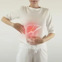 Kobieta trzyma się za brzuch, gdzie widoczny jest zarys wątroby z czerwonym podświetleniem, sugerującym ból pod prawą łopatką.