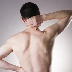 Mężczyzna z bólem karku i pleców, objawy stenozy kanału kręgowego.