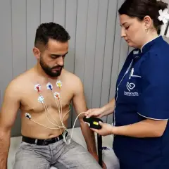 Mężczyzna z elektrodami na klatce piersiowej podczas badania holter ekg. Pielęgniarka podłącza urządzenie.