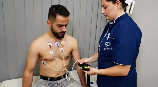 Mężczyzna z elektrodami na klatce piersiowej podczas badania holter ekg. Pielęgniarka podłącza urządzenie.