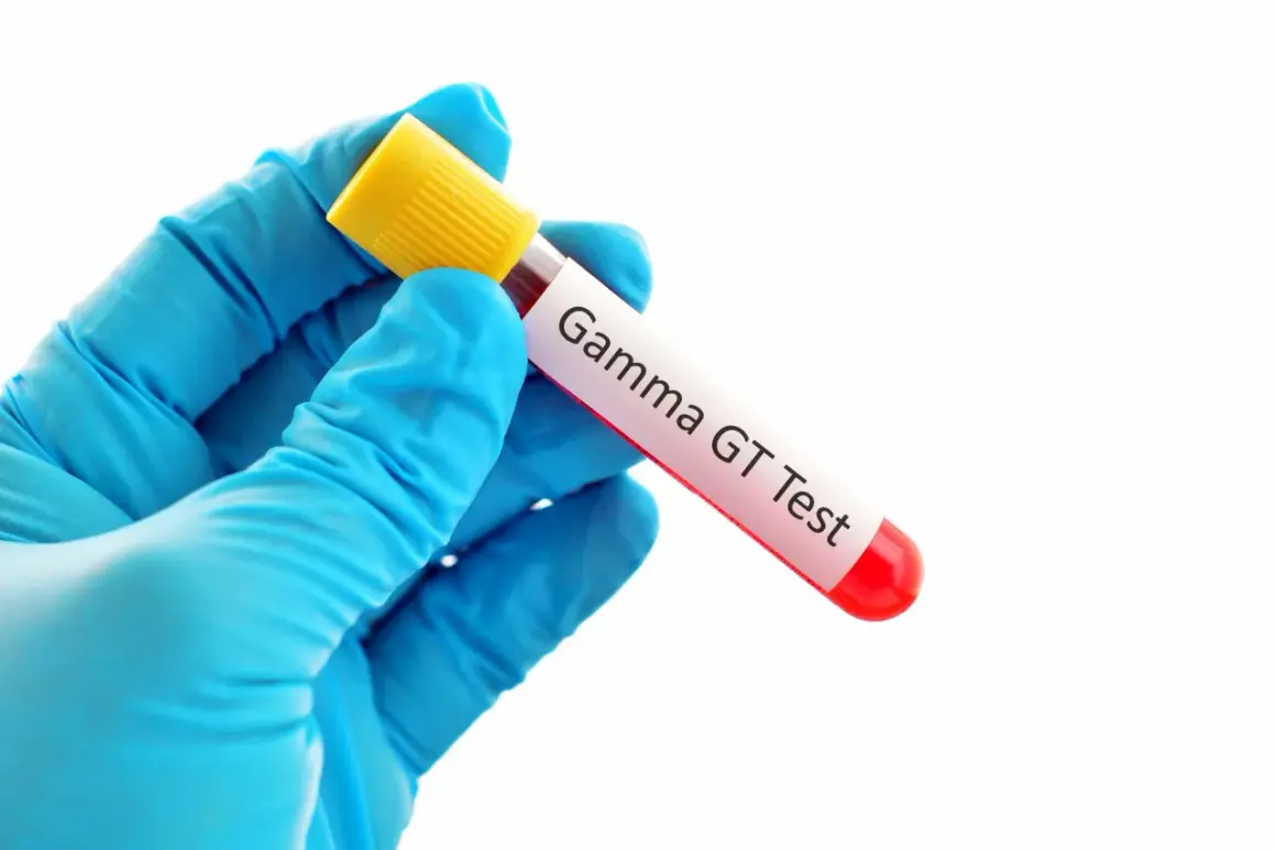 Ręka w niebieskiej rękawiczce trzyma probówkę z krwią do badania Gamma GT.