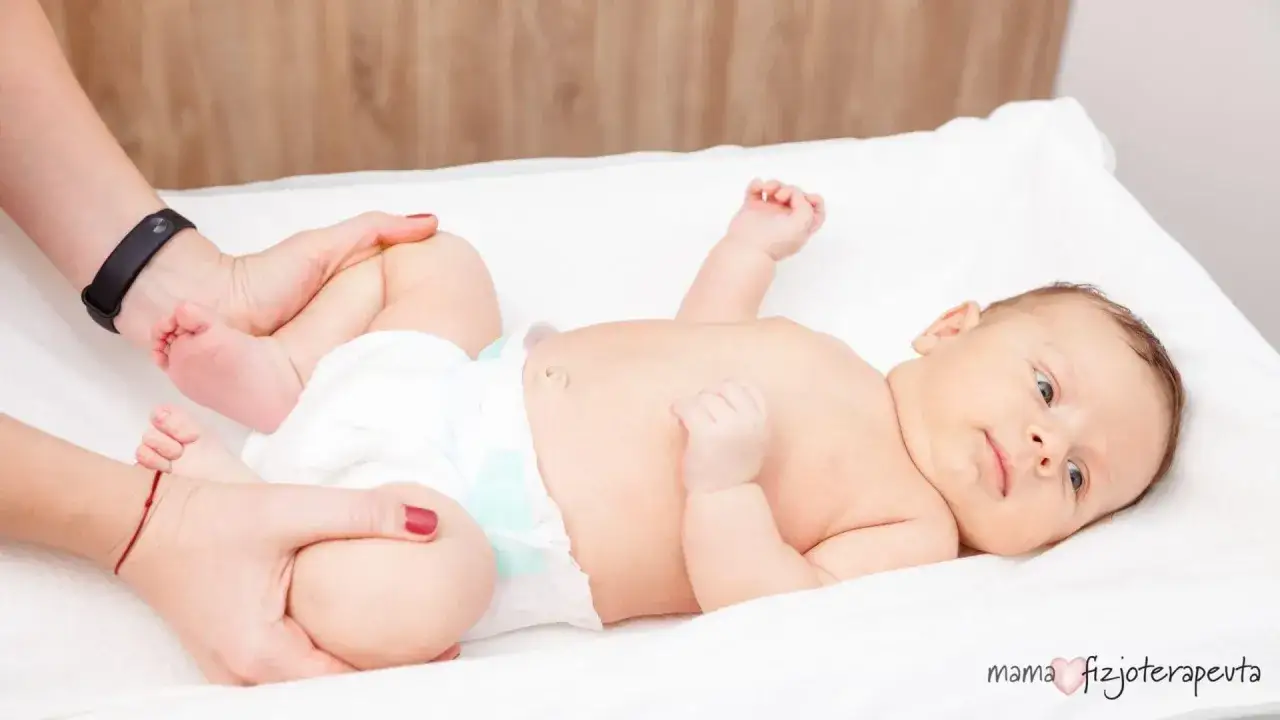 Fizjoterapeuta delikatnie układa nóżki niemowlęcia, sprawdzając jego bioderka pod kątem dysplazji.