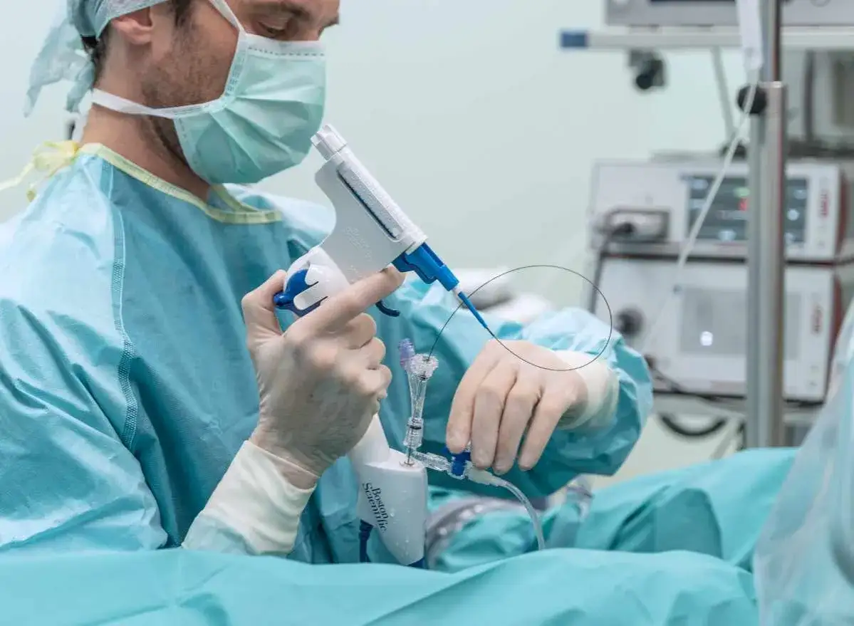 Chirurg w masce i rękawiczkach wykonuje biopsję prostaty za pomocą specjalistycznego przyrządu.