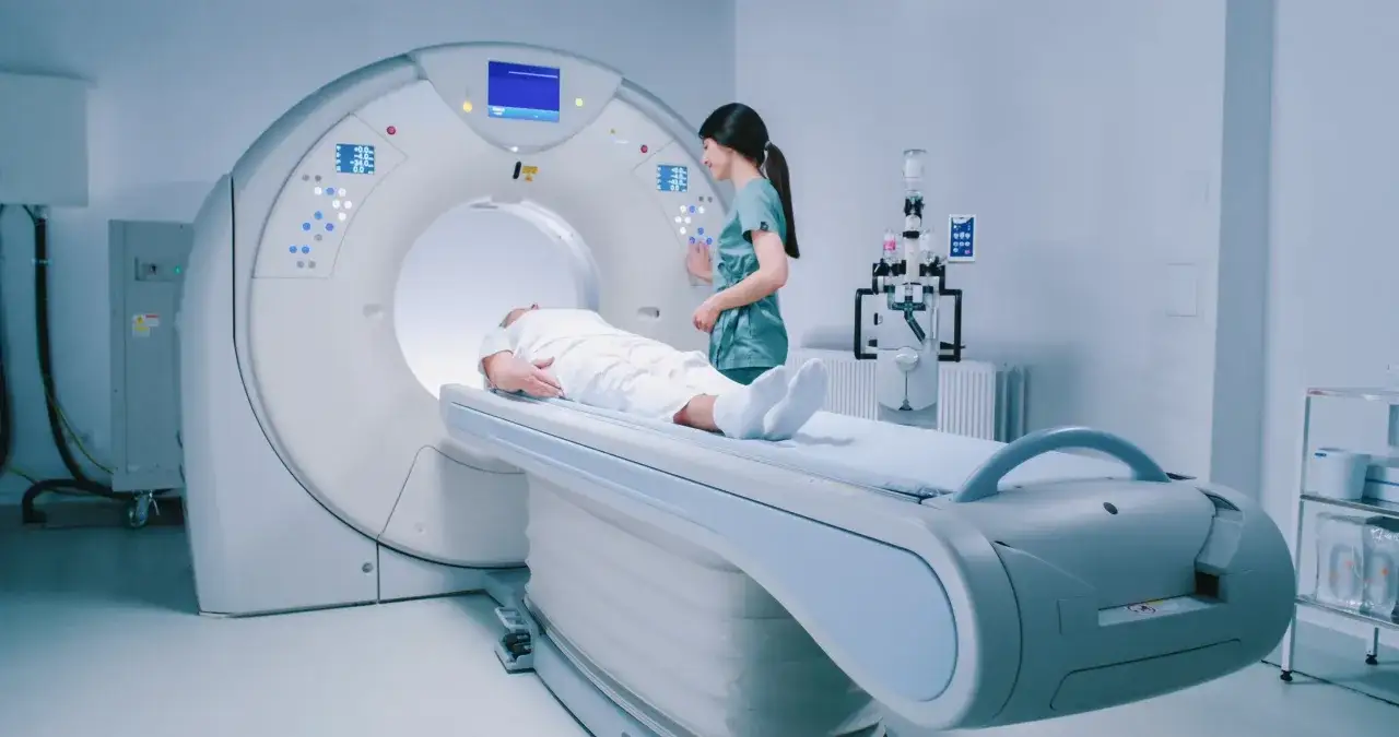 Pacjent leży na łóżku rezonansu magnetycznego, a pielęgniarka przygotowuje badanie. Zastanawiasz się, ile trwa rezonans głowy?