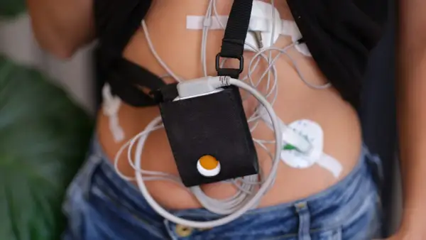 Holter jak się ubrać? Pacjent w dżinsach i czarnej koszulce z przyczepionym urządzeniem monitorującym.