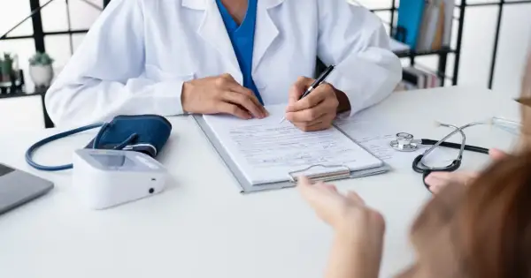 Lekarz notuje objaw kliniczny pacjenta, obok leży stetoskop i ciśnieniomierz.
